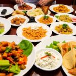 Diverse dishes from various cuisines on a restaurant table.